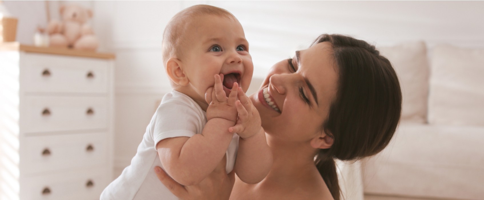 Мати тримає немовля на руках і усміхається.