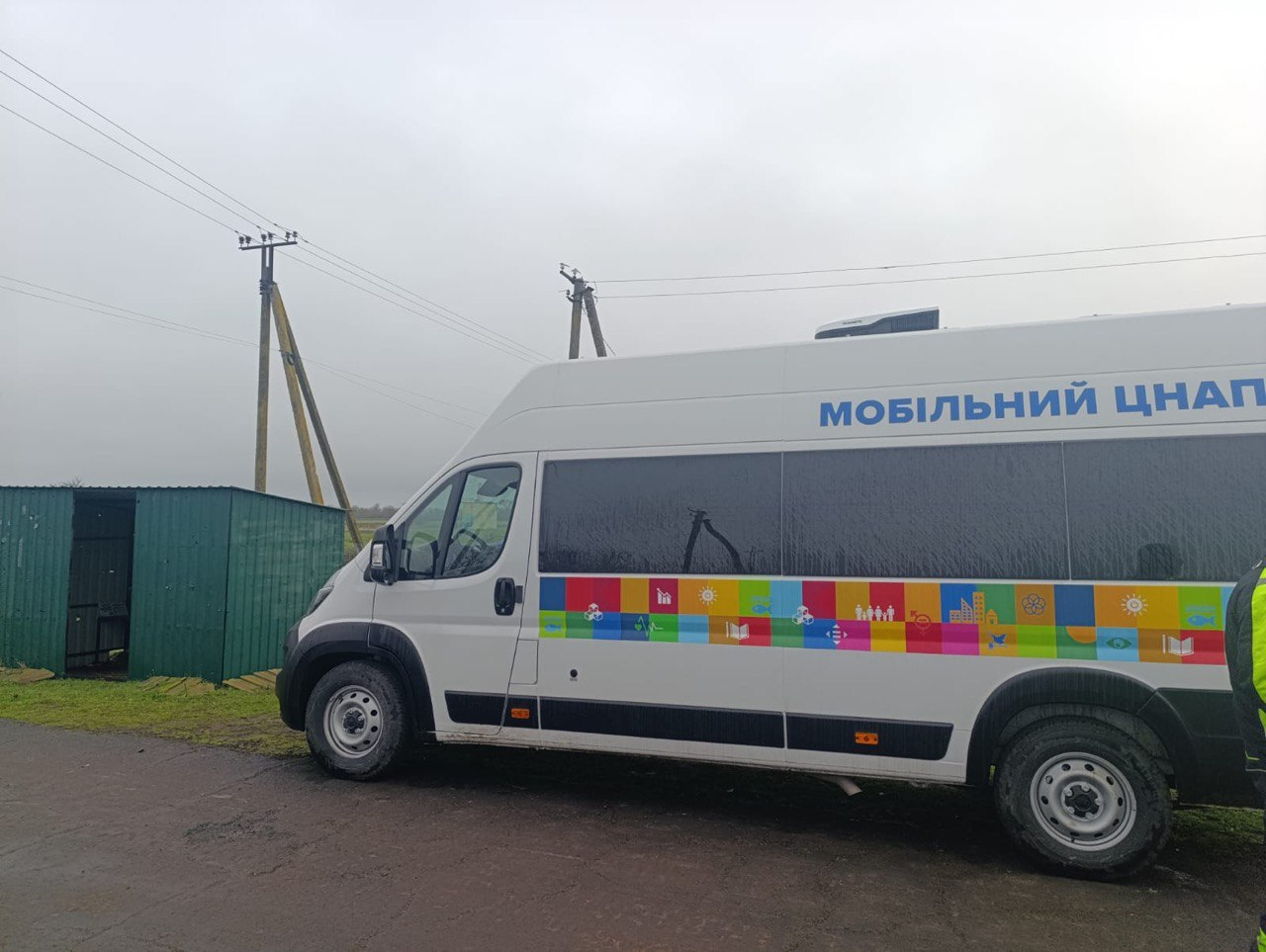 Білий мікроавтобус із написом: МОБІЛЬНИЙ ЦНАП, припаркований на узбіччі дороги в похмуру погоду.