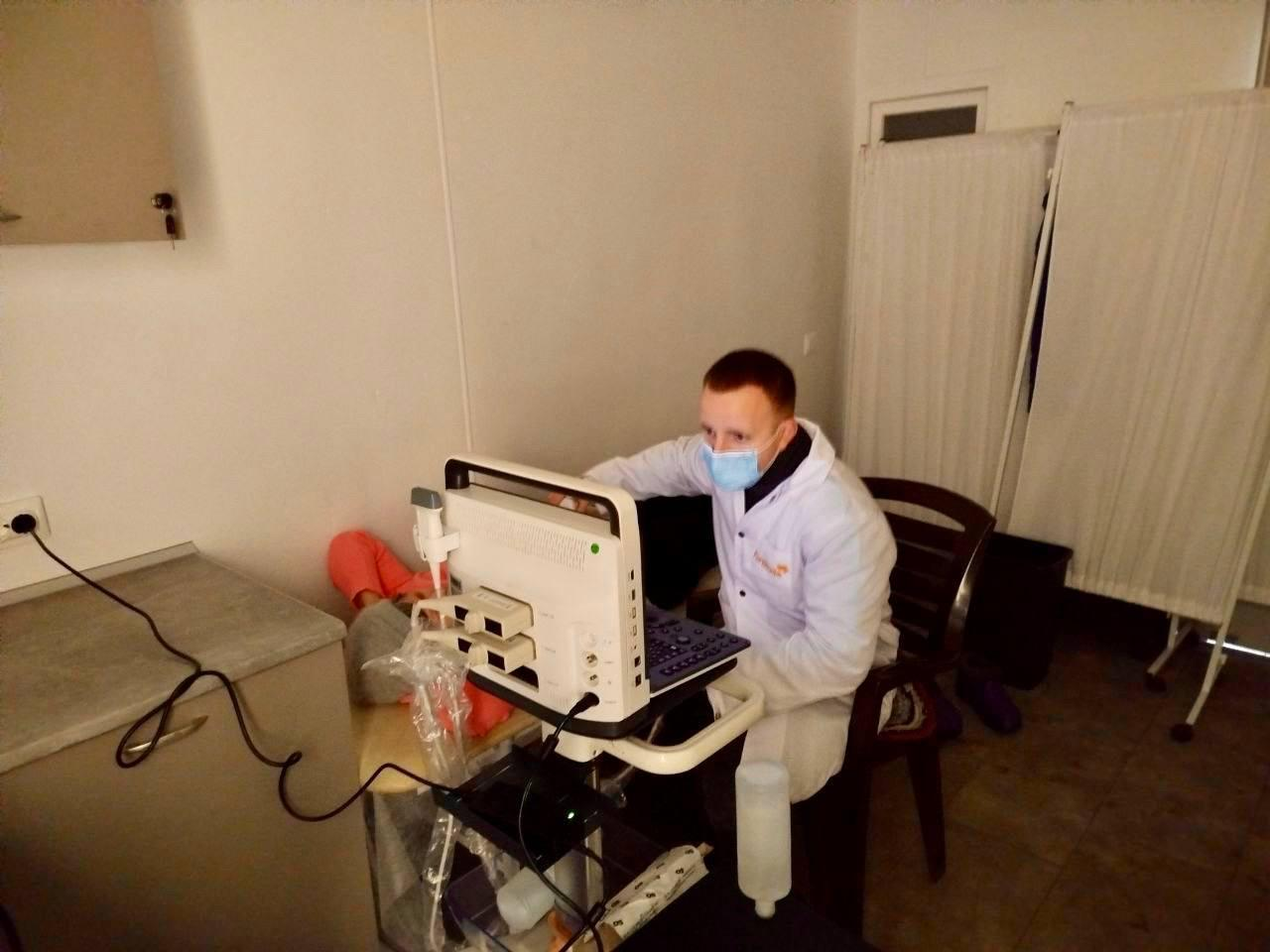 Лікар працює за монітором сучасного портативного апарату УЗД, на якому відображається результат сканування внутрішніх органів.