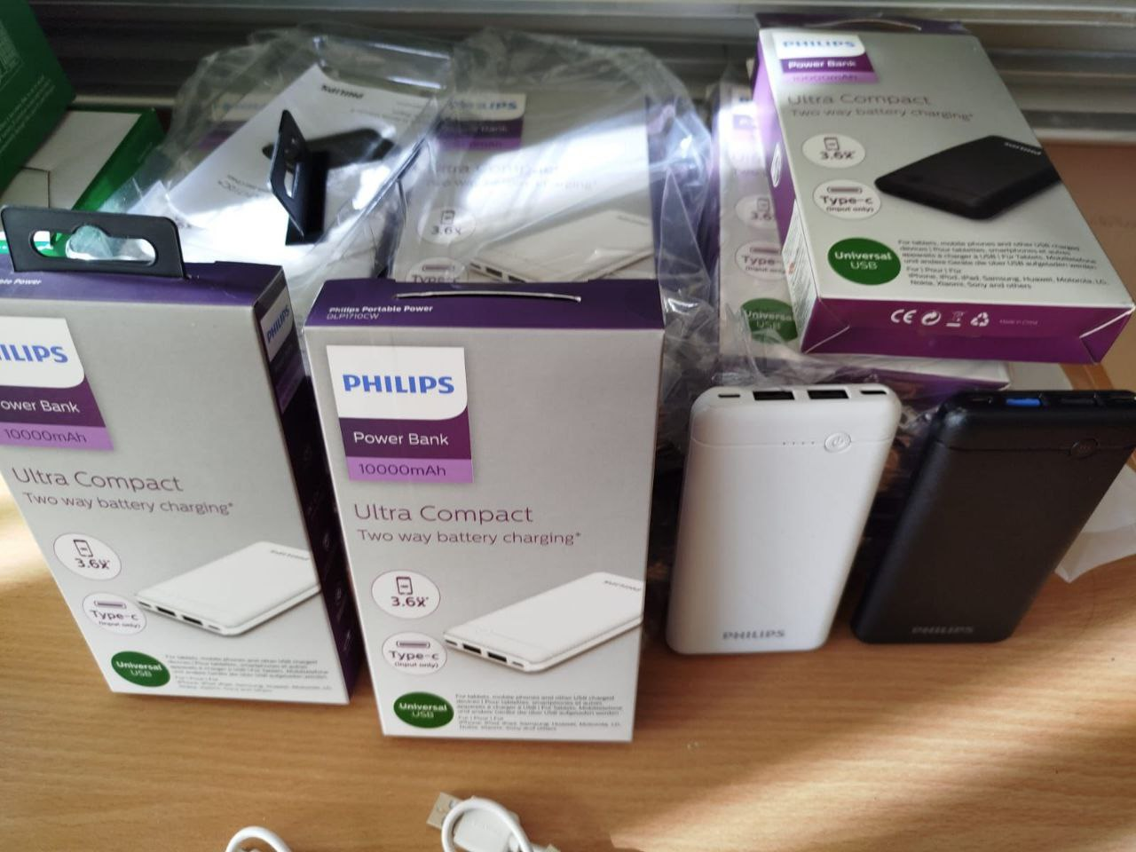 Великий план портативних зарядних пристроїв (павербанків) Philips у білих коробках та без упаковок. На упаковці зазначена ємність 10 000 мАг та модель «Ultra Compact». Поруч лежать розпаковані пристрої білого та чорного кольорів.
