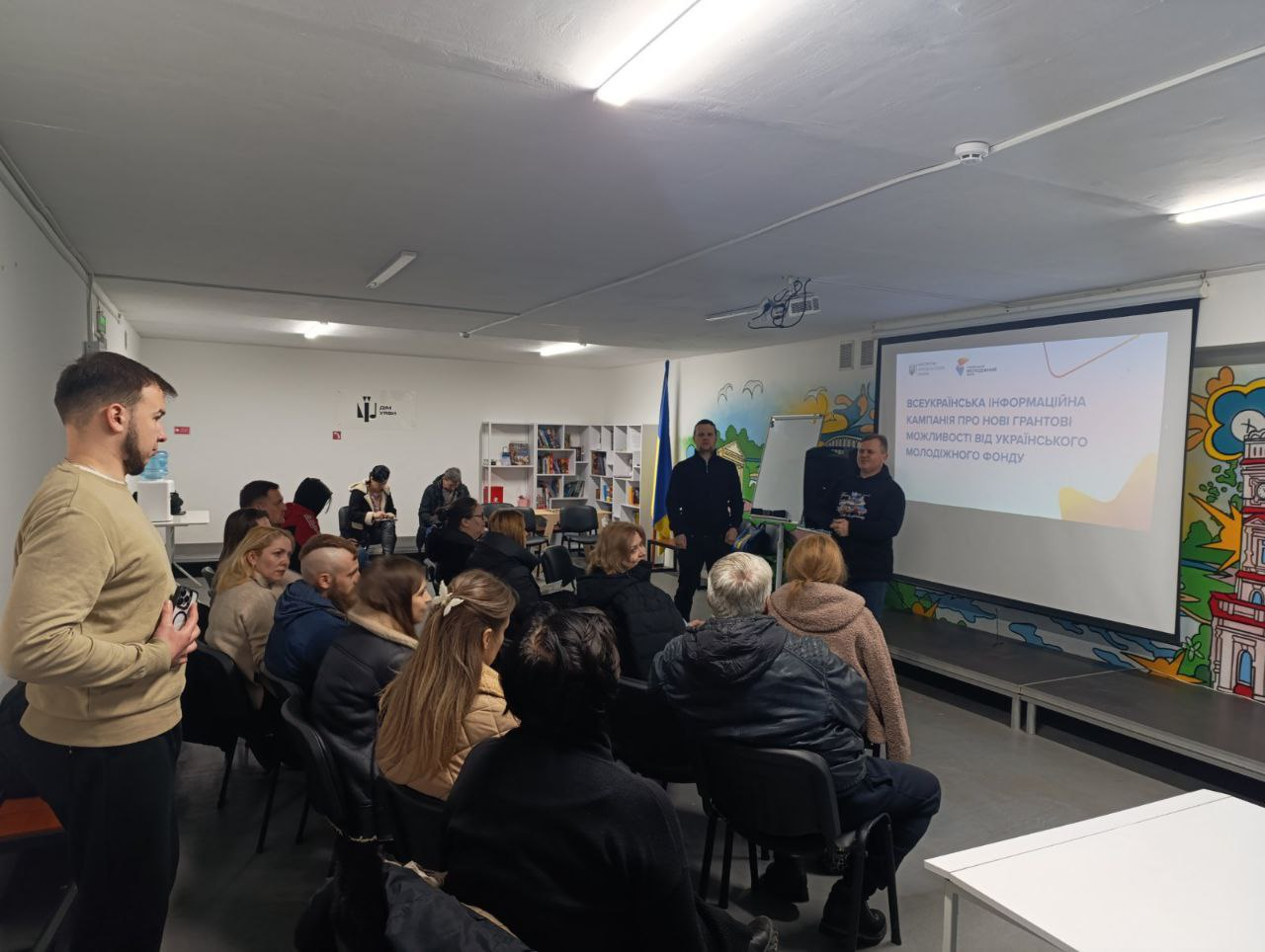 Спікер проводить захід для аудиторії в приміщенні з проєктором. На екрані відображено заголовок про всеукраїнську інформаційну кампанію щодо нових грантових можливостей від Українського молодіжного фонду.