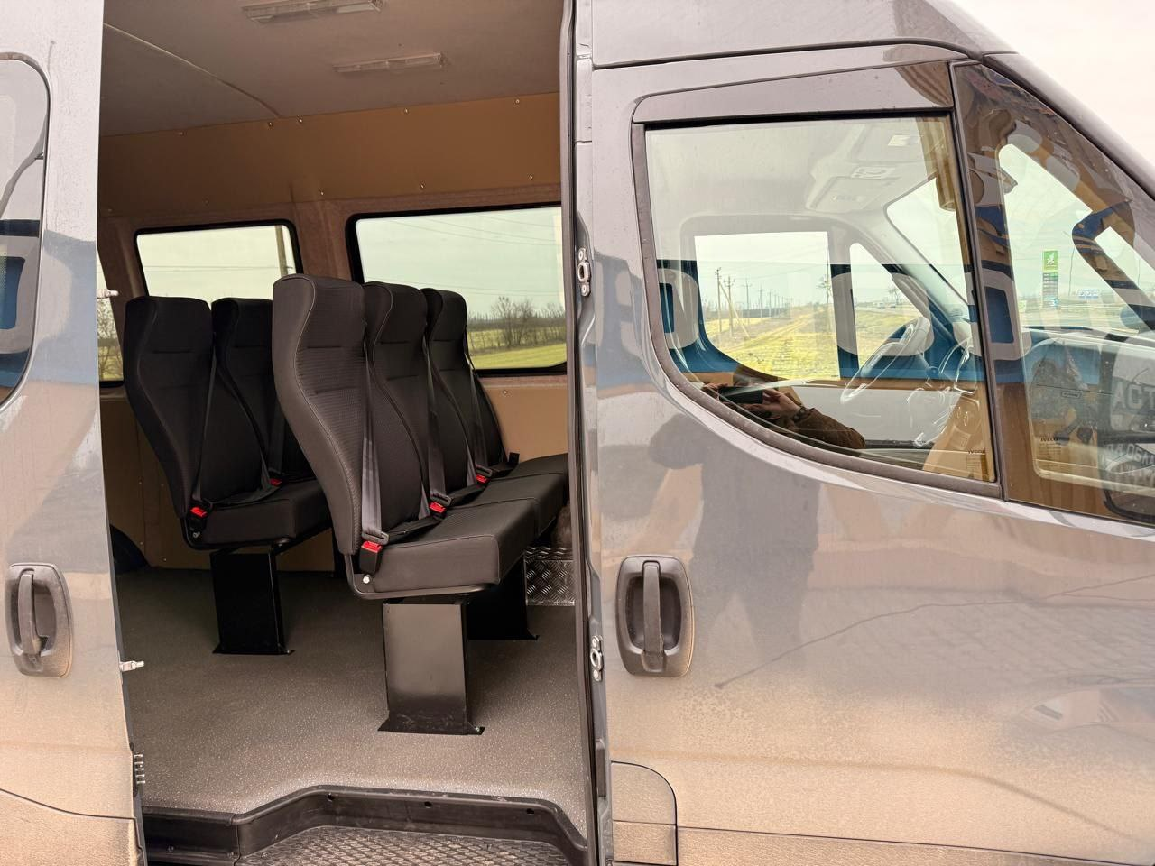 Інтер'єр мікроавтобуса через відчинені бічні двері. У салоні встановлені сучасні чорні пасажирські крісла з триточковими пасками безпеки.