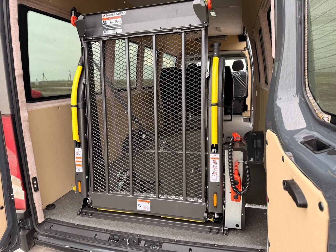 Вигляд салону через задні двері мікроавтобуса, де встановлено спеціалізовану металеву платформу-підйомник для транспортування людей на кріслах колісних.