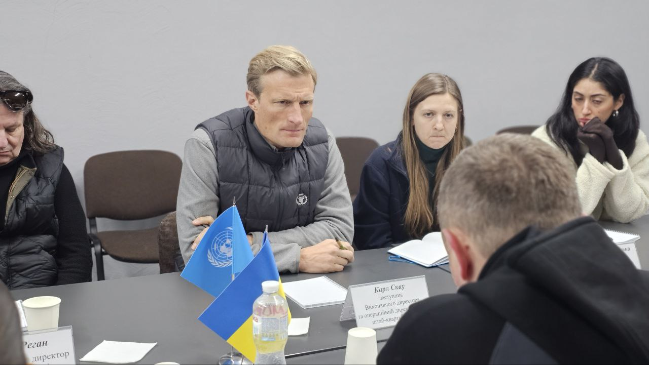 Учасники офіційної зустрічі за столом під час переговорів. На передньому плані видно настільні прапорці України та ООН, а також іменну табличку одного з представників організації.