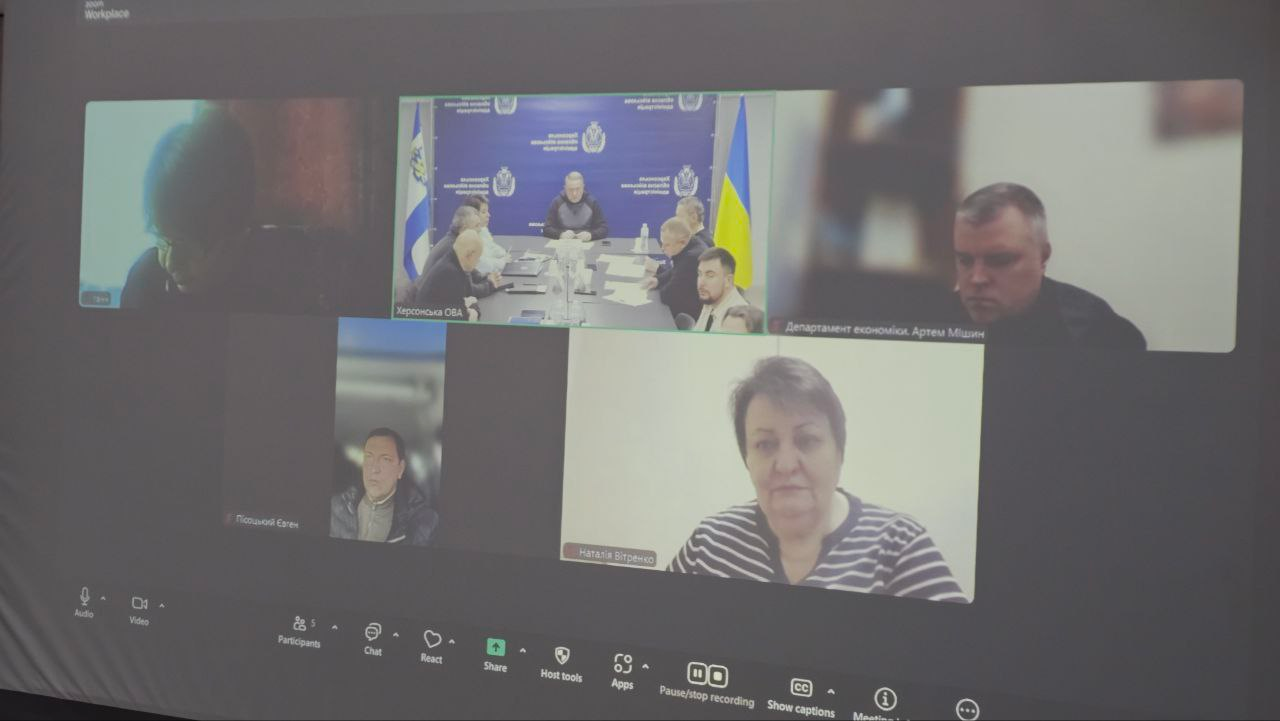 Скриншот екрана під час онлайн-наради у Zoom. На відео видно п’ять вікон із учасниками зустрічі та спільний зал із синьо-жовтою символікою на фоні. У нижній частині екрана розташована панель інструментів відеозв'язку.