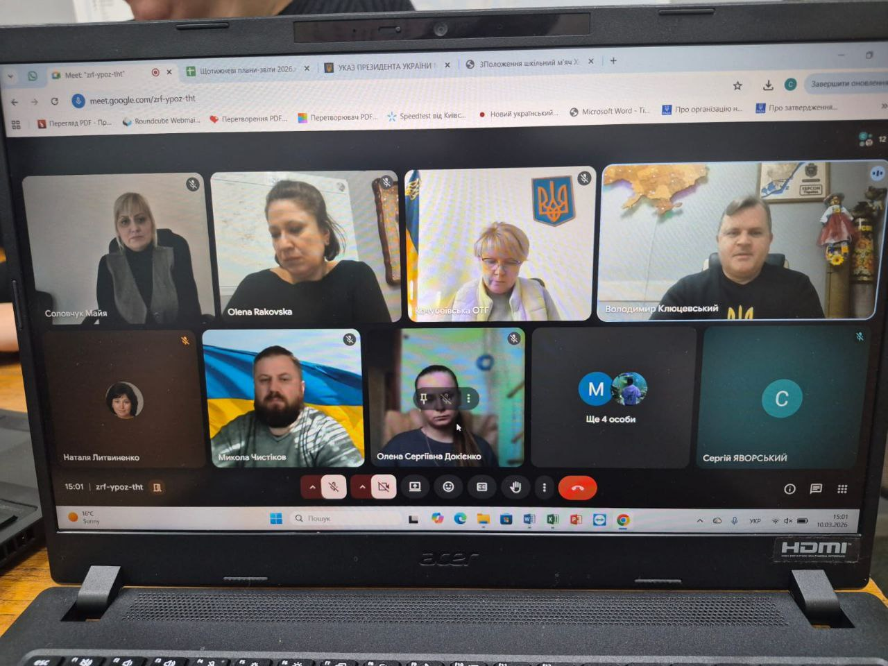 Ноутбук із відкритою онлайн-конференцією в Google Meet. На екрані сітка з відео учасників та елементи керування викликом.