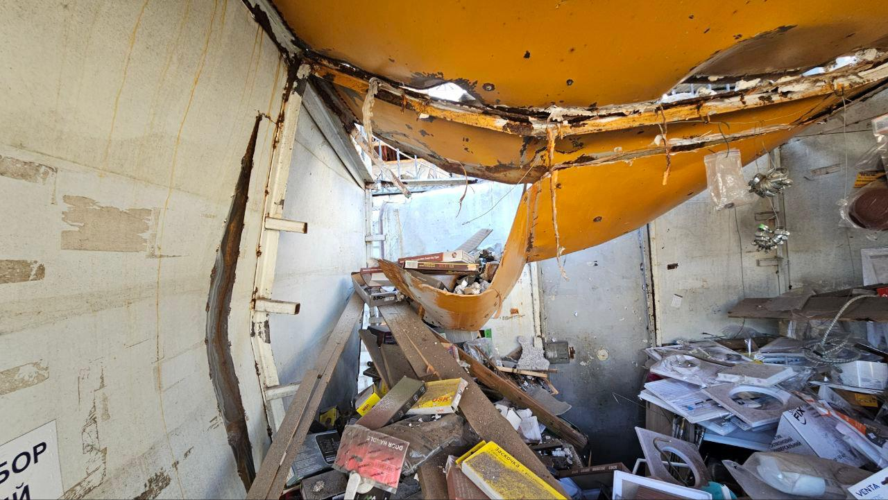 Внутрішній простір зруйнованого приміщення з обваленою жовтою металевою стелею та розкиданим уламками будівельних матеріалів.