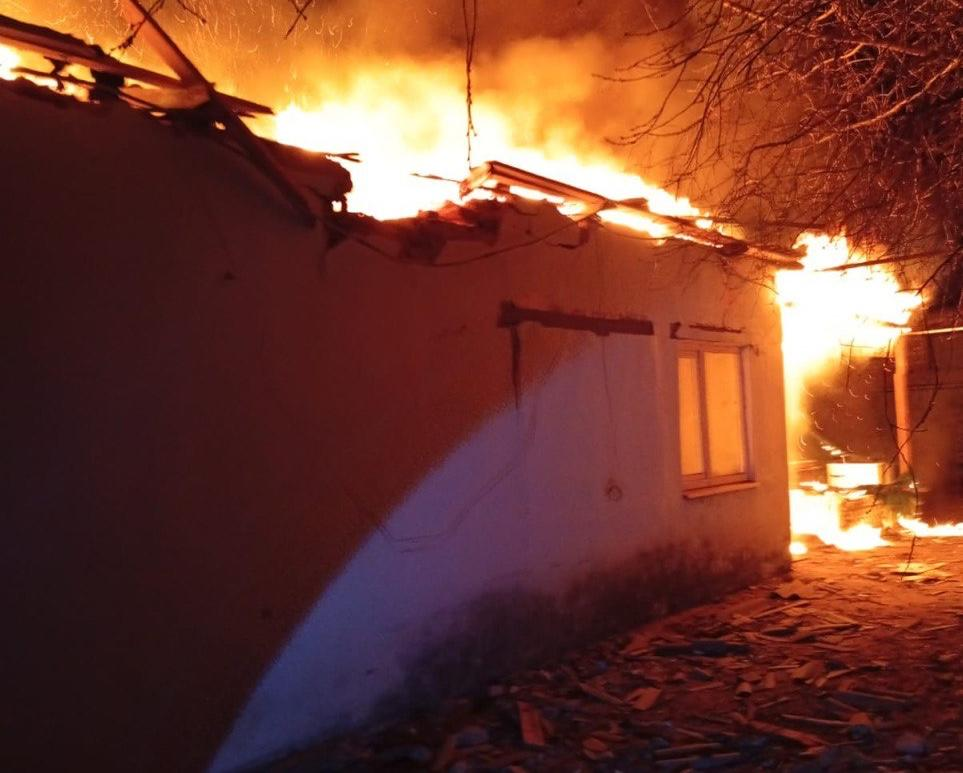 Потужна пожежа в приватному будинку в нічний час. Вогонь повністю охопив дах будівлі та частину прилеглої території, утворюючи заграву.