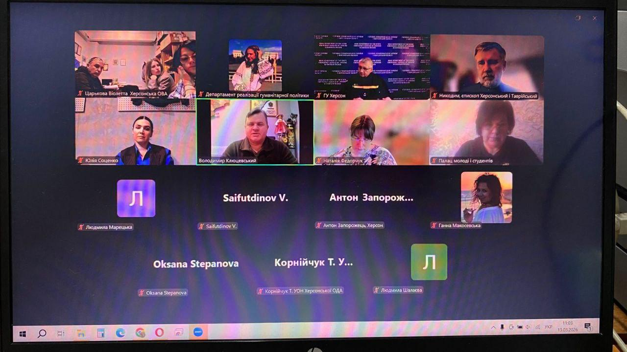 Скриншот екрана ноутбука з вікном відеоконференції у Zoom або Google Meet. У сітці виклику видно вісім вікон із учасниками (чоловіками та жінками) та кілька іконок користувачів без увімкнених камер. Підписи вказують на представників Херсонської ОВА та інших установ.