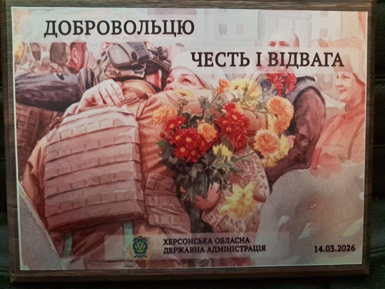 Пам'ятний постер «Добровольцю — честь і відвага» від Херсонської ОДА. На зображенні — обійми українського військового з близькою людиною, що тримає квіти. Дата — 14.03.2026.