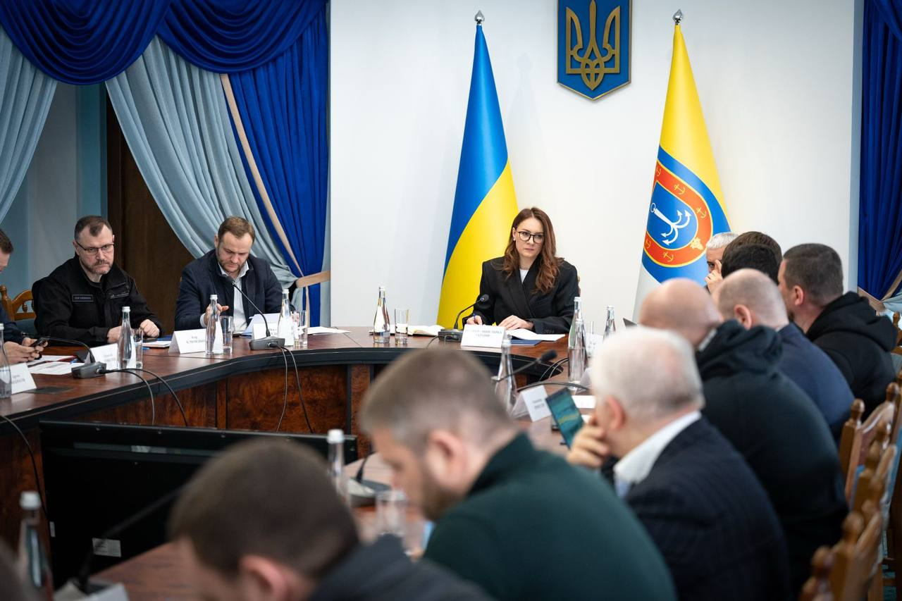 Офіційна нарада за великим круглим столом під головуванням жінки. На фоні — Державний Прапор України та офіційна символіка, на столах — мікрофони, ноутбуки та документи.