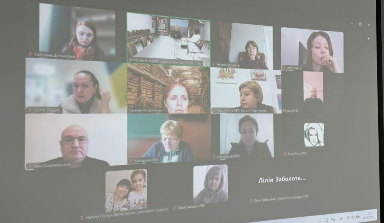 Скриншот онлайн-наради у форматі відеоконференції, спроєктований на екран. У сітці виклику видно вікна з багатьма учасниками, підписами їхніх імен та назвами організацій.