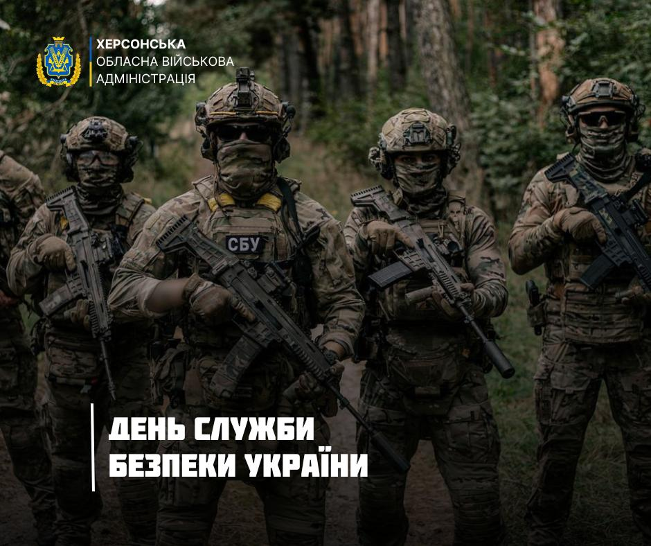 Спецпризначенці СБУ у повному спорядженні зі зброєю на тлі лісу. На фото логотип Херсонської ОВА та вітальний напис до Дня Служби безпеки України.