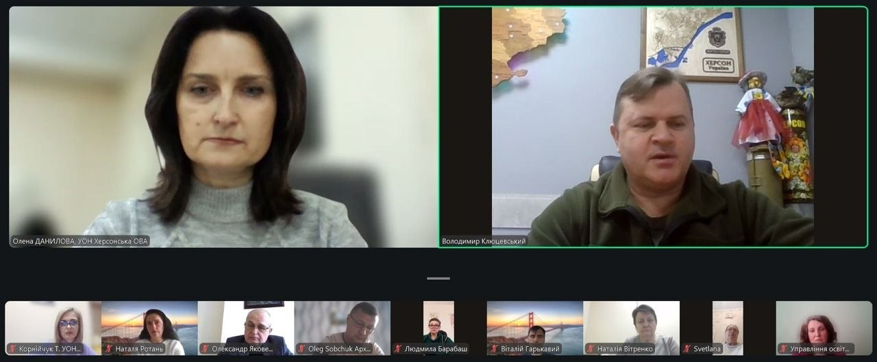 Скриншот онлайн-наради у форматі відеоконференції. На екрані двоє основних доповідачів (жінка та чоловік у військовій формі), а також нижня панель із декількома меншими вікнами інших учасників. На фоні в одного з учасників видно патріотичну символіку та карту України.