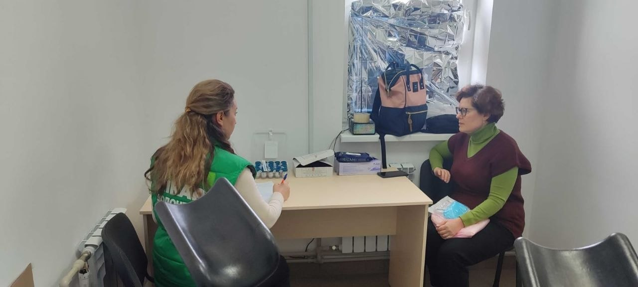 Консультація спеціаліста у зеленому жилеті з логотипом Casers для жінки в офісному приміщенні.