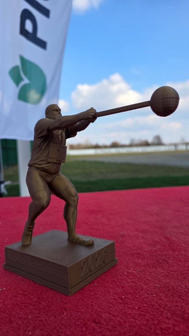 Спортивна статуетка бронзового кольору, що зображує метальника молота в момент замаху. На підставці викарбувано напис «2024», а сама нагорода стоїть на червоній поверхні на фоні стадіону та прапора.