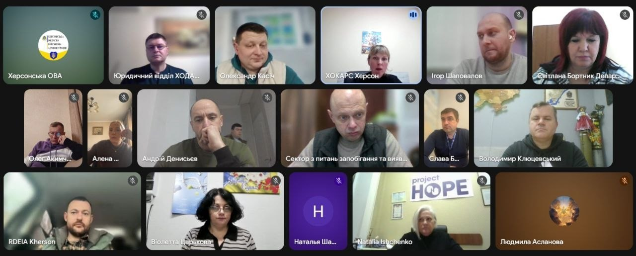Скриншот онлайн-наради у форматі відеоконференції з великою кількістю учасників. Вікна користувачів містять відеозображення людей, логотипи організацій (зокрема Херсонської ОВА та Project HOPE) або текстові підписи з іменами та назвами відділів.