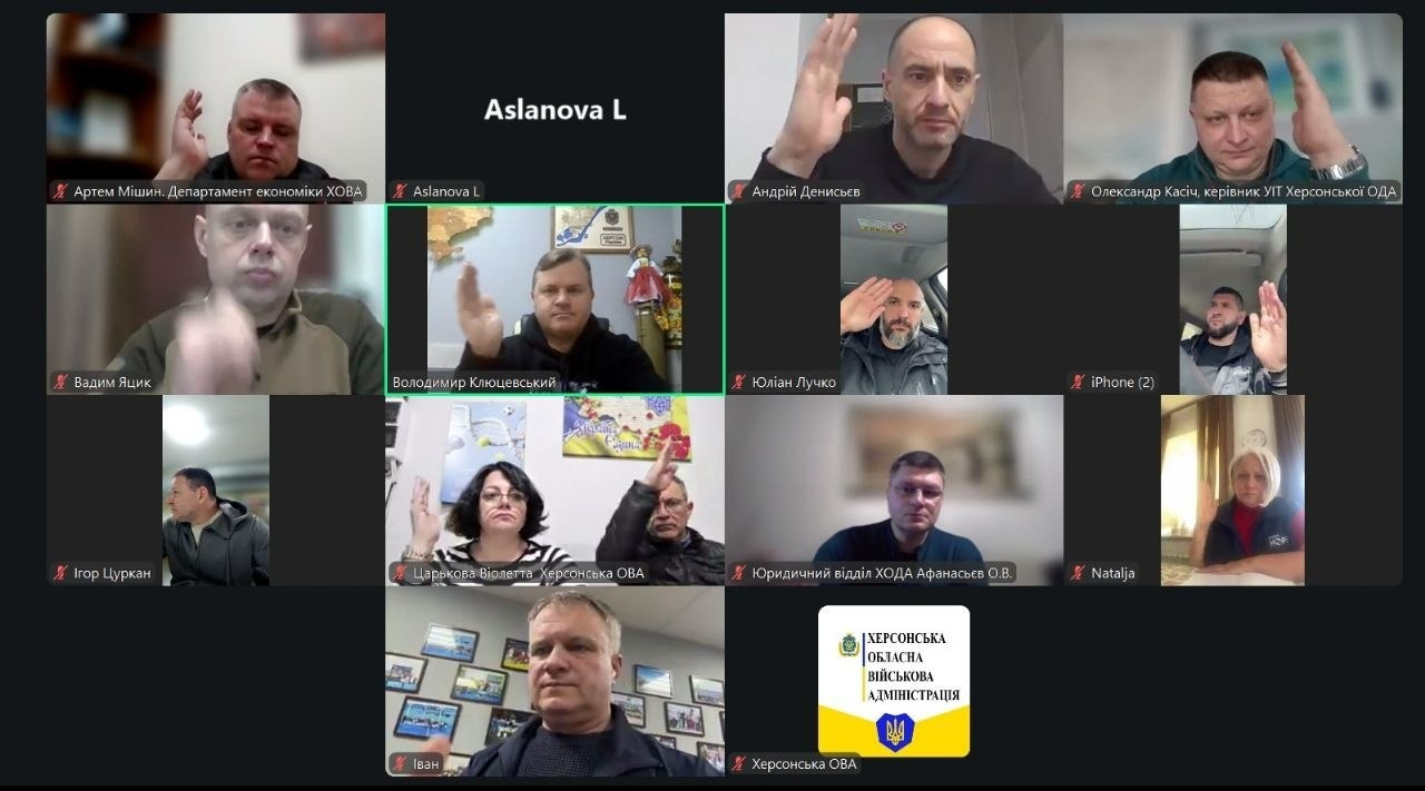 Скриншот робочої онлайн-наради в режимі відеоконференції. Учасники, що знаходяться в окремих вікнах виклику, одночасно піднімають руки для голосування. Одне з вікон містить логотип і герб Херсонської обласної військової адміністрації.