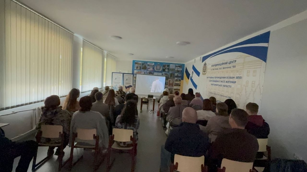 Зустріч групи людей у залі координаційного центру, де вони дивляться на великому екрані кінокартину.