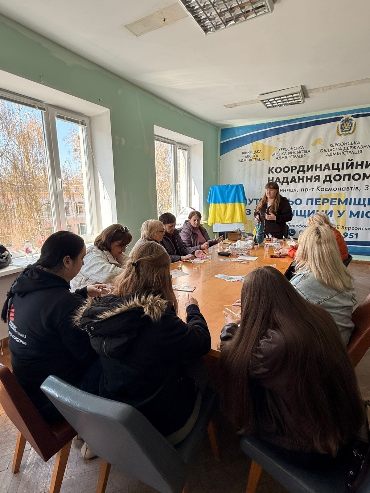 Група людей за великим столом під час зустрічі у координаційному центрі надання допомоги.