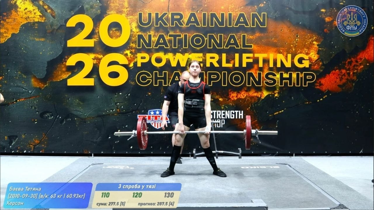 Спортсменка виконує станову тягу на чемпіонаті України з пауерліфтингу 2026 року. На фоні — банер з логотипом ФПУ, а внизу екрана — графічне табло з результатами спроб та інформацією про виступ.