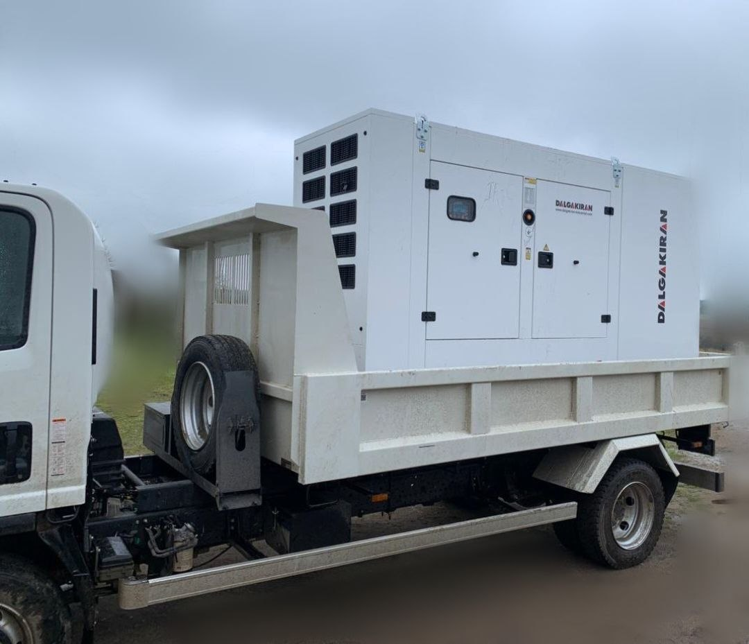 Великий білий промисловий генератор марки «Dalgakiran», завантажений у кузов білої вантажівки.