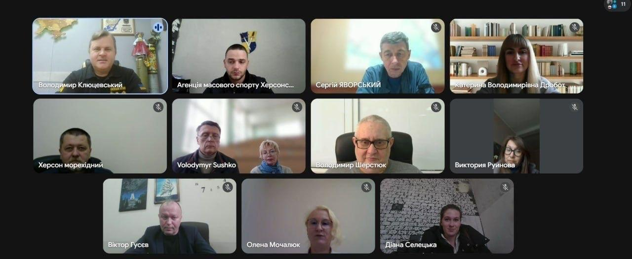 Скриншот онлайн-наради в Zoom із сіткою відеовікон учасників. На екрані представлено 11 віконець, у яких видно людей у різних приміщеннях: кабінетах, на фоні книжкових полиць або світлих стін. Кожне вікно підписане ім'ям учасника або назвою організації.