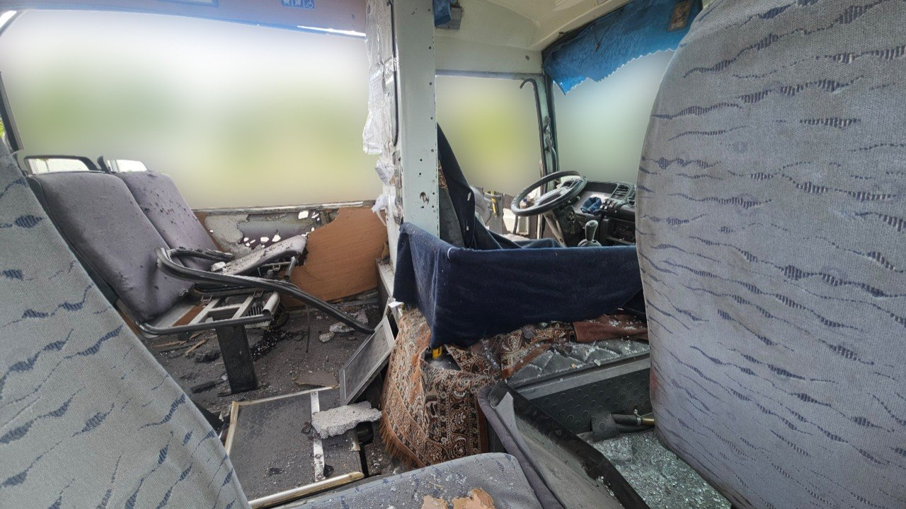 Вид на місце водія та передню частину салону пошкодженого автобуса. Усередині розбите скло, посічена обшивка та поламані поруччя сидінь. Вікна затушовані.