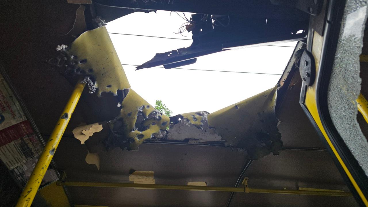 Вигляд зсередини автобуса на наскрізну пошкоджену ділянку в даху з розірваною обшивкою та слідами уламків чи обгорання.