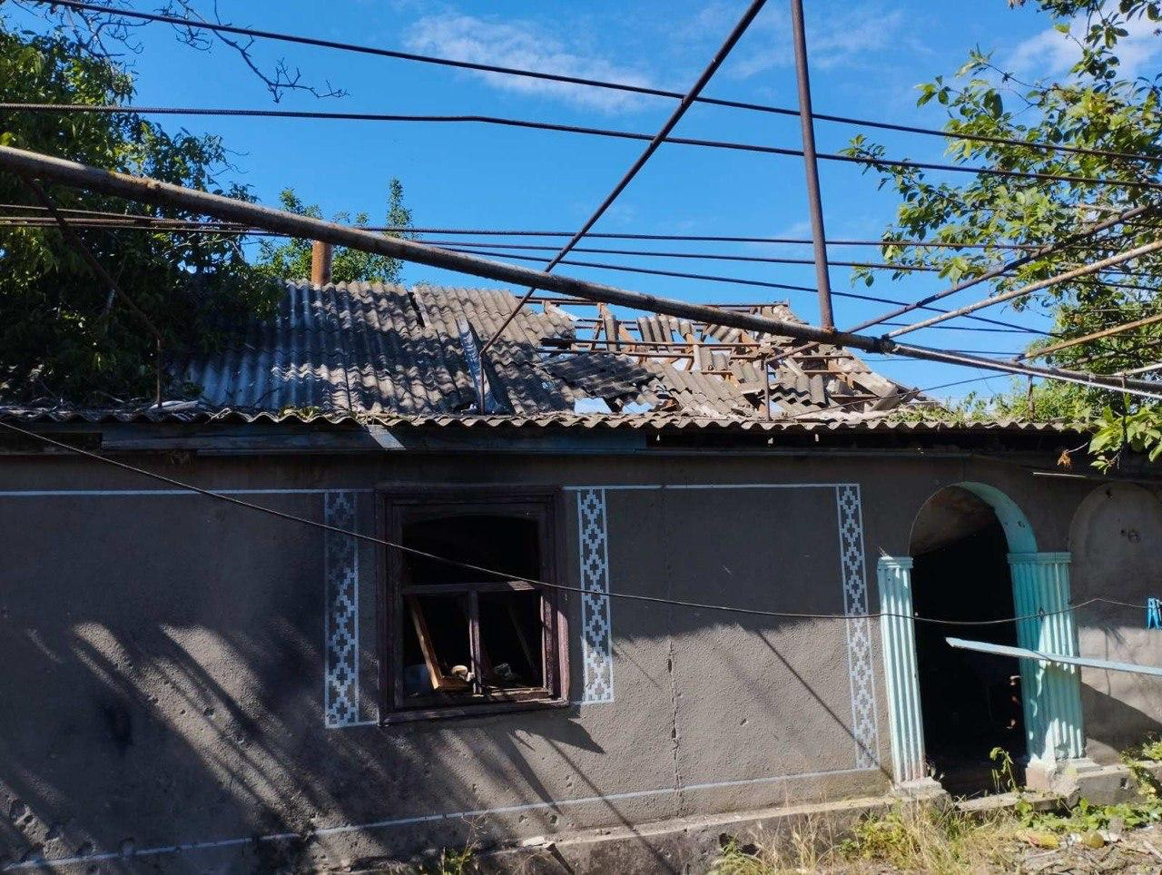 Одноповерховий житловий будинок із пошкодженим шиферним дахом, вибитими вікнами та поваленими металевими конструкціями на передньому плані.