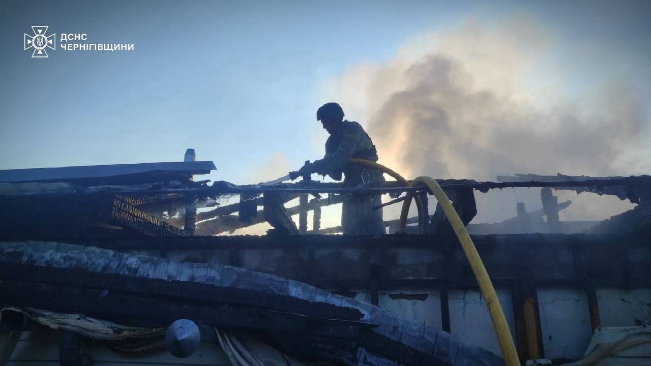 Рятувальник у захисному спорядженні гасить пожежу на зруйнованому даху будівлі, з якого йде густий дим. У лівому верхньому кутку розміщено емблему та напис «ДСНС ЧЕРНІГІВЩИНИ».