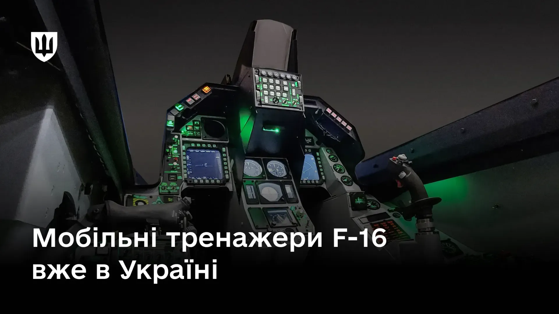 Кабіна авіаційного симулятора F-16 із підсвіченою приладовою панеллю, екранами та важелями керування в темному приміщенні. Поверх зображення нанесено напис «Мобільні тренажери F-16 вже в Україні» та логотип у лівому верхньому кутку.