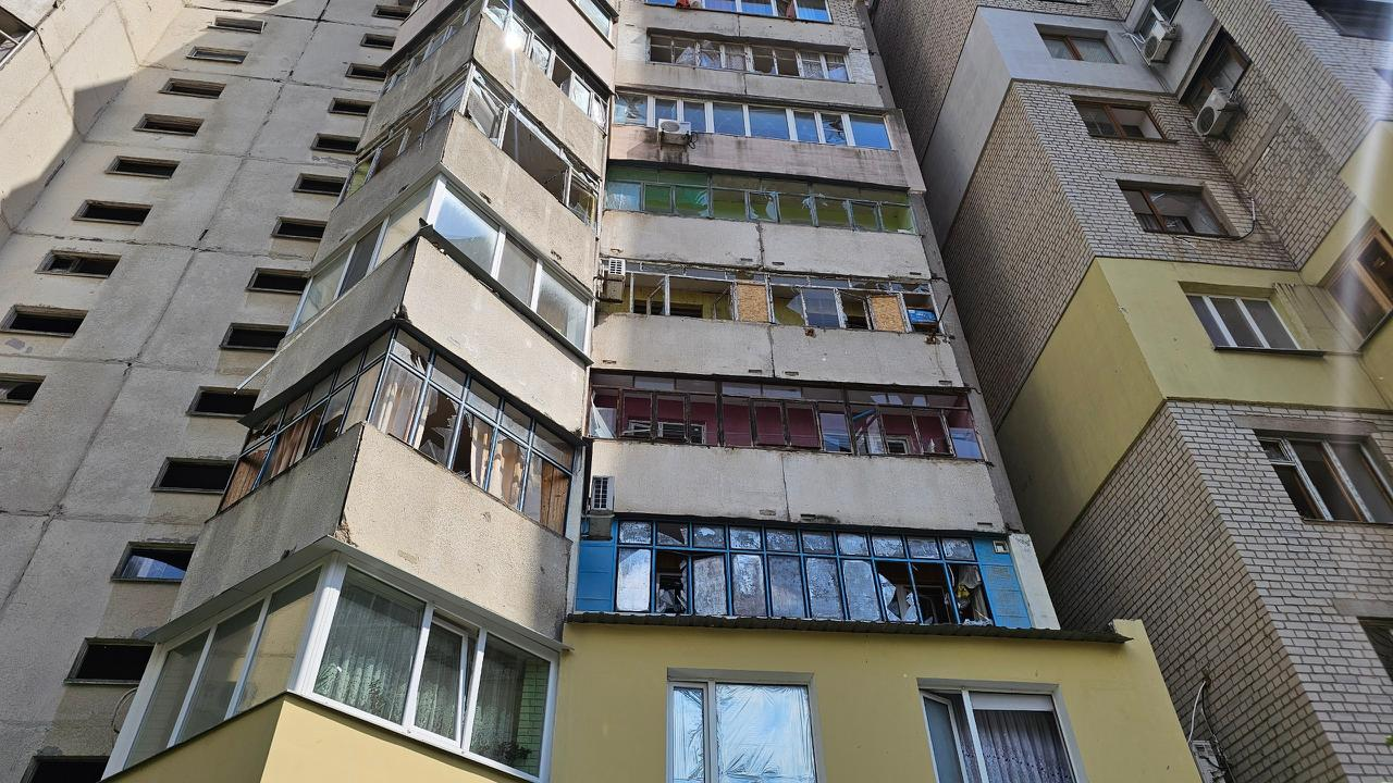 Багатоповерховий житловий будинок із численними пошкодженнями внаслідок обстрілу. На кількох поверхах видно повністю вибиті вікна, зруйновані балконні рами та пошкоджені стіни будівлі.