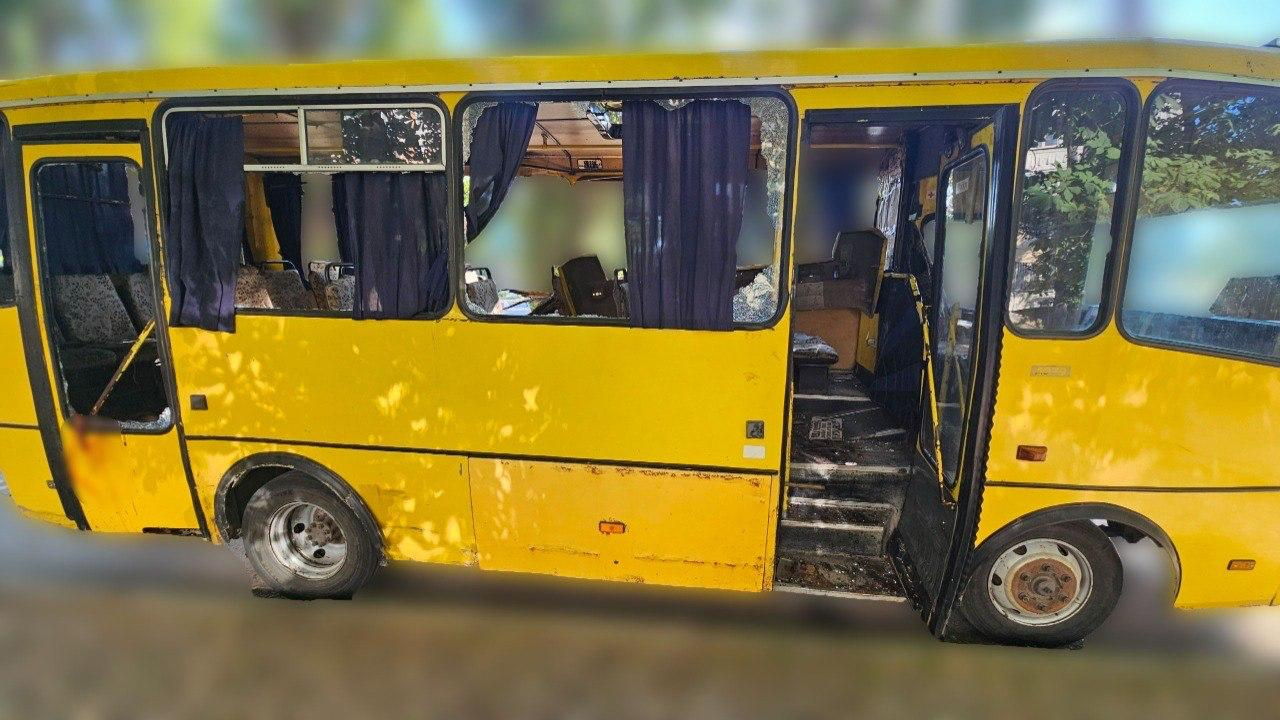 Пошкоджений жовтий пасажирський автобус (маршрутка) із вибитим склом у вікнах та дверях.