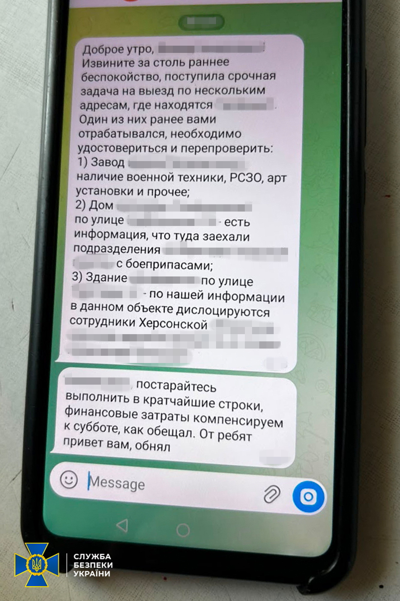 Екран мобільного телефона, на якому відкрито чат месенджера з текстовими повідомленнями російською мовою. У тексті йдеться про збір інформації щодо дислокації військової техніки та підрозділів, окремі назви та адреси об'єктів затушовані, а у лівому нижньому кутку фото розміщено офіційний логотип Служби безпеки України.