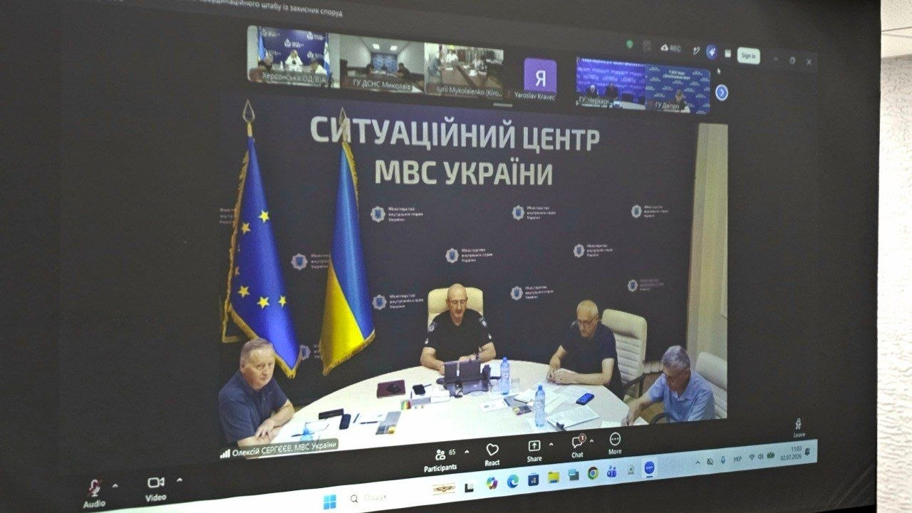Знімок екрана комп'ютера під час онлайн-наради у форматі відеоконференції. Головне вікно транслює пряме включення із Ситуаційного центру МВС України, де за круглим столом сидять чоловіки у формі та цивільному одязі на тлі прапорів України та Європейського Союзу. У верхній частині екрана відображаються маленькі віконця інших учасників трансляції, а знизу — панель керування дзвінком.