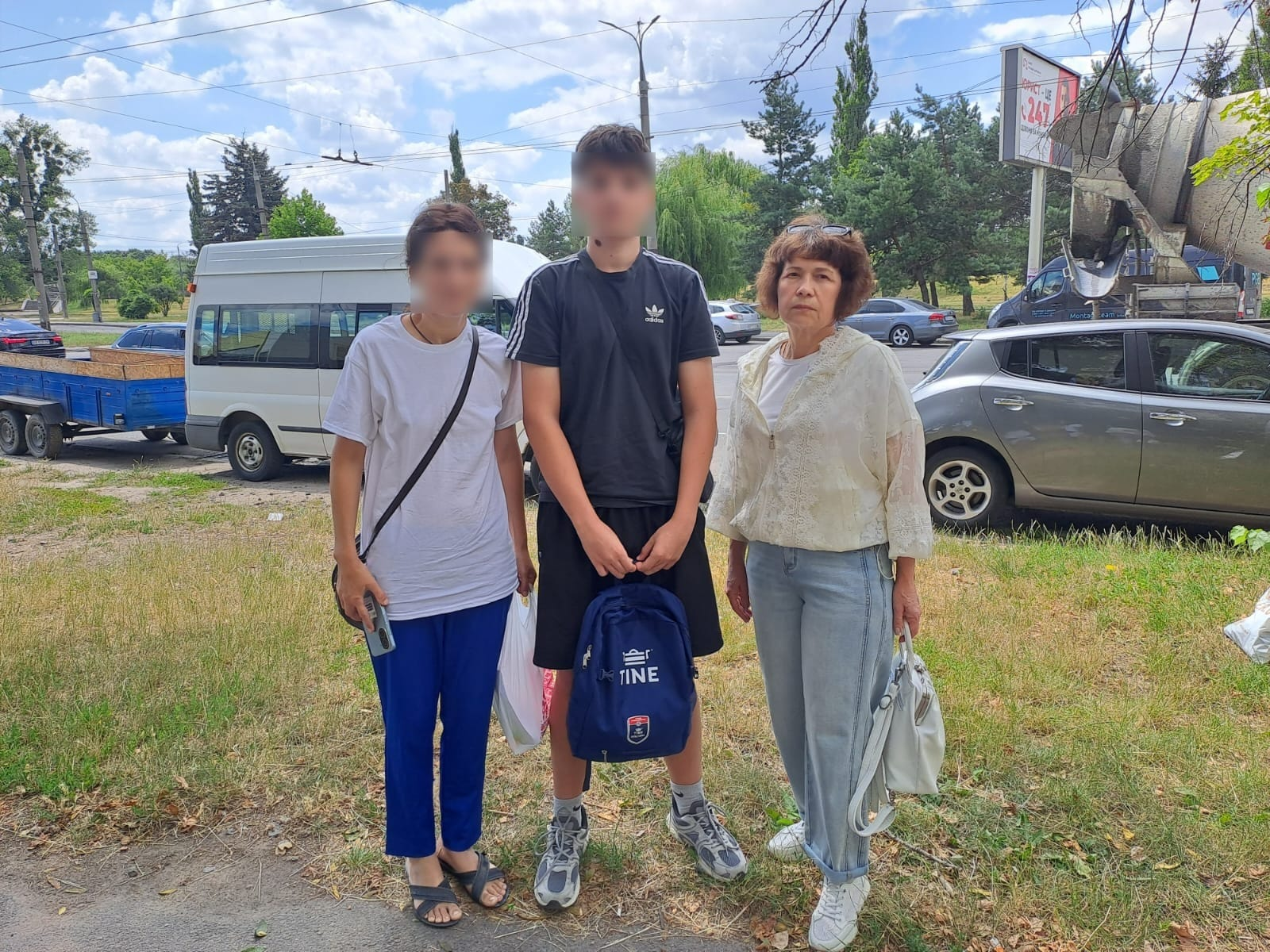 Начальниця служби у справах дітей Каланчацької селищної ради та жінка з підлітком, які евакуювалися з тимчасово окупованої території Херсонщини й знайшли прихисток у Вінницькій області, стоять разом на узбіччі дороги у сонячний день.