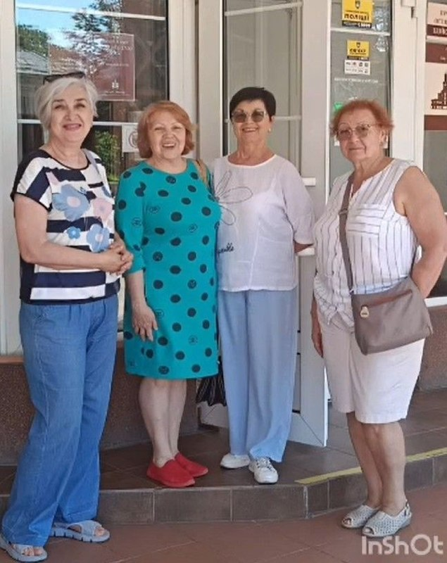 Чотири літні жінки посміхаються, стоячи на ґанку Івано-Франківського краєзнавчого музею перед початком благодійної екскурсії.