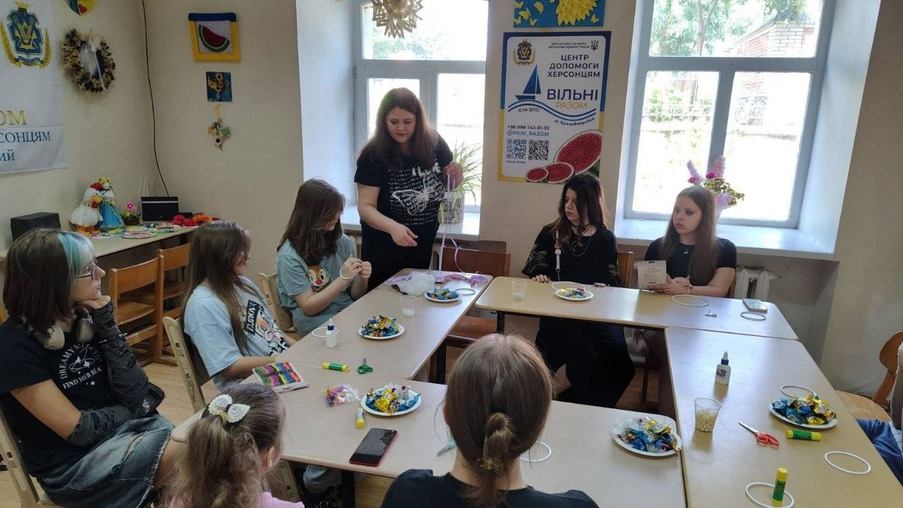 Майстер-клас із виготовлення «ловців снів» для підлітків-переселенців із Херсонщини в координаційному центрі «Вільні разом» у Кропивницькому, організований Верхньорогачицькою СВА: учасники сидять за творчим столом із солодощами та матеріалами для рукоділля, слухаючи інструктаж майстрині.
