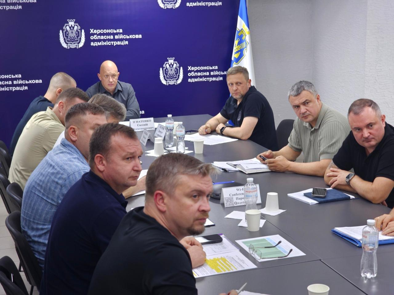 Учасники онлайн-наради в залі засідань ХОВА працюють за столом, де крайнім ліворуч на задньому плані сидить начальник Херсонської МВА Ярослав Шанько, по центру — заступник начальника ОВА Євгеній Ігнатенко, а праворуч у чорній футболці поло — перший заступник начальника ОВА Дмитро Бутрій.