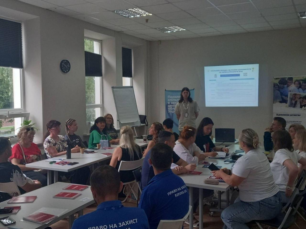 Робоча зустріч у світлій аудиторії, де фахівці БФ «Право на захист», ГО «Десяте квітня» та ГО «Рефектіо» надають юридичну підтримку, психологічні консультації та проводять групові заняття для учасників заходу, які слухають спікера біля екрана з презентацією.