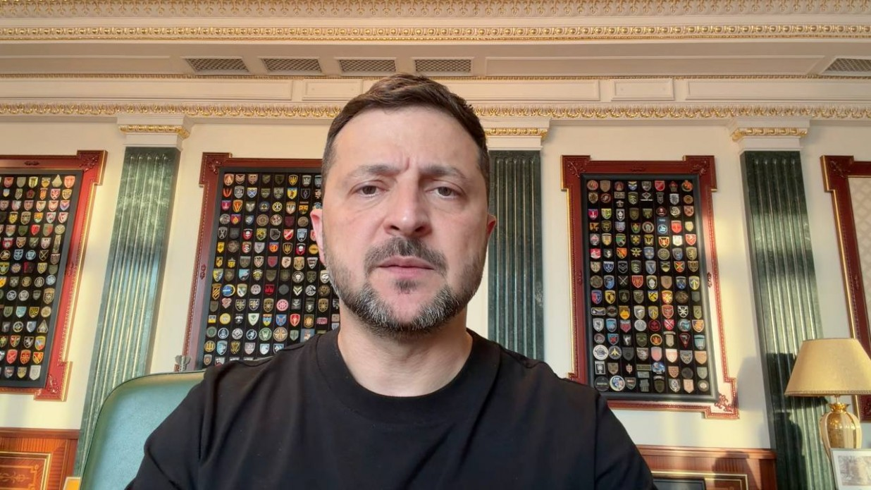 Президент України Володимир Зеленський під час відеозвернення на тлі офіційного інтер'єру кабінету з колонами та дошками, на яких розміщено колекцію військових шевронів різних підрозділів.