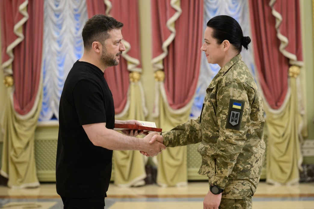Президент України Володимир Зеленський тисне руку та відзначає державною нагородою медикиню у камуфляжній формі під час зустрічі з бойовими й цивільними медиками напередодні Дня медичних працівників.