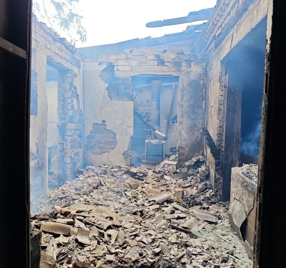 Наслідки пожежі в житловому будинку у селі Хрещенівка після атаки російського дрона. У будівлі повністю знищено дах, стіни сильно пошкоджені, а підлога засипана великою кількістю уламків шиферу та цегли. У кімнатах ще тримається дим.