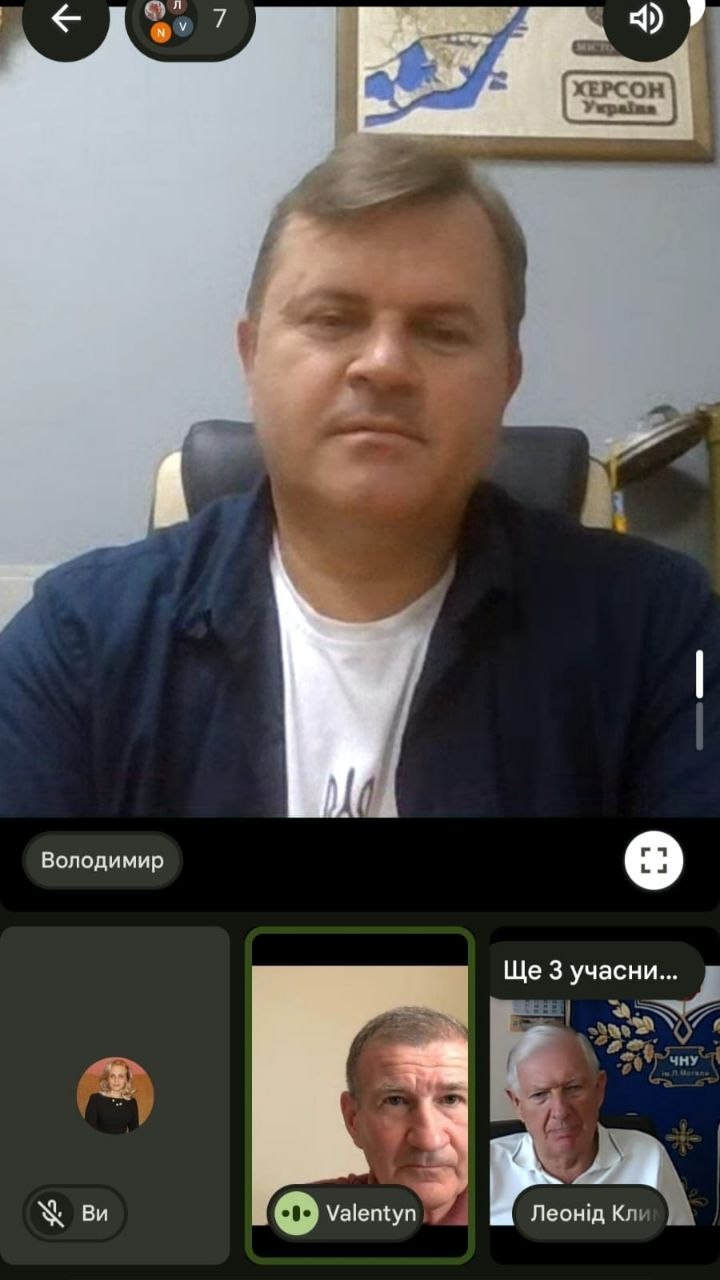 Скриншот робочої онлайн-наради в Google Meet, яку проводить заступник голови Херсонської ОДА Володимир Клюцевський. У головному вікні — Володимир Клюцевський, на задньому плані видно карту із написом «Херсон, Україна». Нижче розташовані вікна інших учасників зустрічі, зокрема ректора ЧНУ імені Петра Могили Леоніда Клименка, під час обговорення переміщення Херсонського обласного фахового спортивного коледжу до Миколаєва.