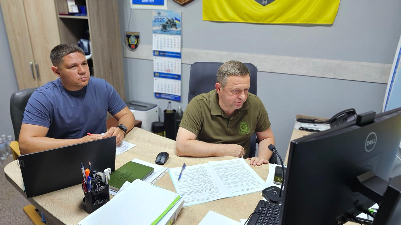 Перший заступник начальника Херсонської ОВА Дмитро Бутрій (праворуч у зеленій футболці поло) та директор Департаменту розвитку сільського господарства та зрошення Дмитро Юнусов (ліворуч у синій футболці) за робочим столом проводять онлайн-нараду щодо проблемних питань аграрного бізнесу Херсонщини.