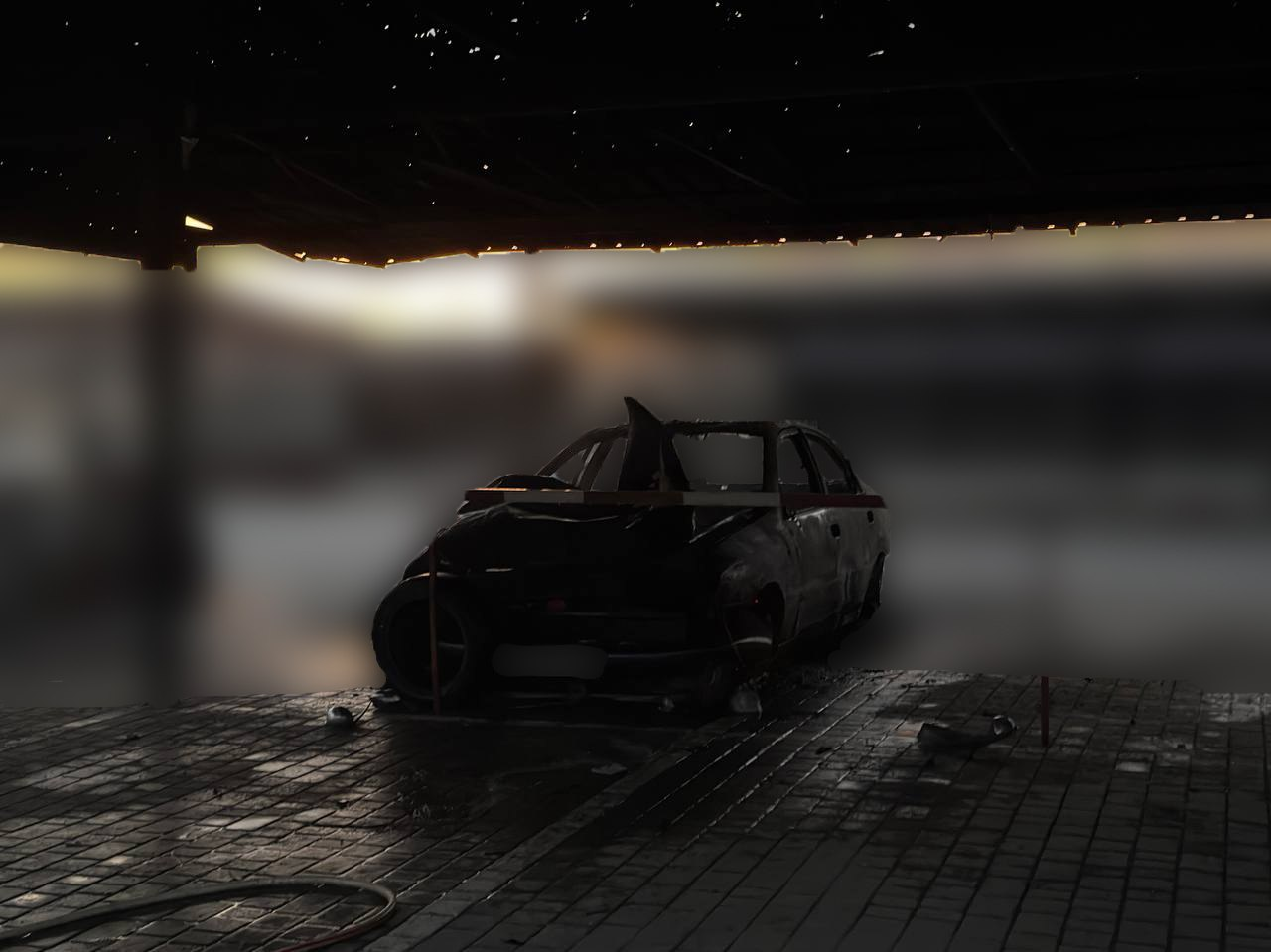 Згорілий вщент цивільний автомобіль у Центральному районі Херсона — наслідок прямого влучання російського безпілотника (БпЛА). Транспортний засіб повністю вигорів і стоїть під пошкодженим накриттям на бруківці.