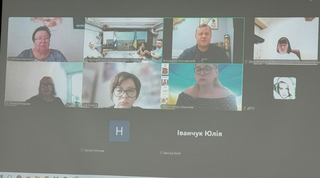Скриншот онлайн-наради робочої групи під керівництвом заступника начальника Херсонської ОВА Володимира Клюцевського щодо створення музею пам’яті під відкритим небом. На екрані відеоконференції відображаються вікна з увімкненими камерами учасників, серед яких директор Департаменту реалізації гуманітарної політики Херсонської ОДА Віолетта Царькова (вікно підписане як «Департамент реалізації гуманітарної політики») та директор Державного архіву Херсонської області Ірина Лопушинська, які обговорюють стан реалізації проєкту.