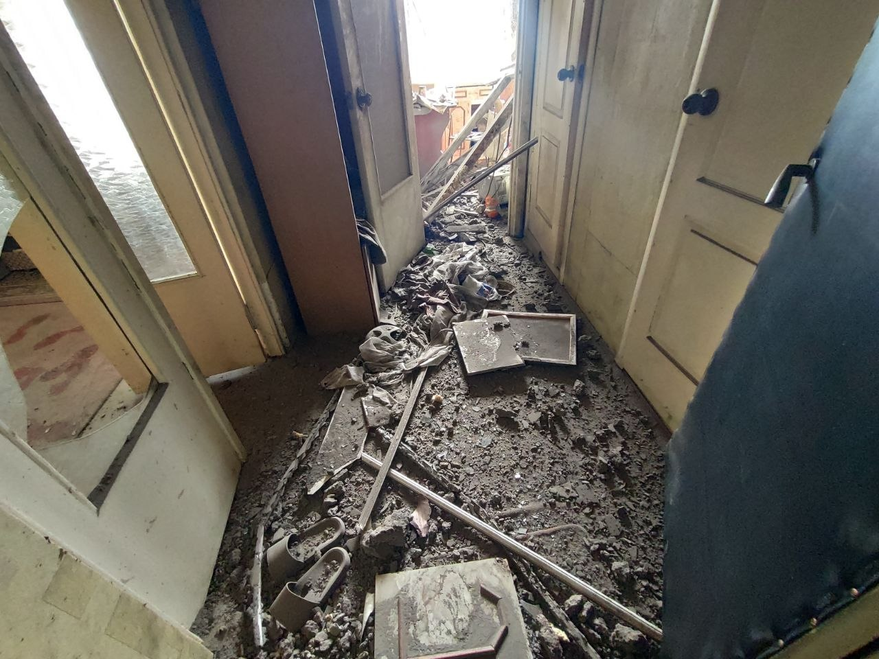 Понівечений коридор квартири в Центральному районі Херсона, повністю засипаний уламками бетону, цегли та побутових речей після нічного влучання російського БпЛА.