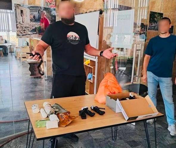 Інструктор Сил спеціальних операцій біля столу з медичними засобами проводить теоретичне заняття з тактичної медицини для переселенців з Херсонщини.